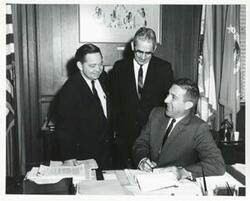 ["Black and white photograph print of Carl Albert with Glen Key watching former Secretary of Interior Stewart Udall signing a contract involving use of water at Arbuckle Reservoir near Sulphur."]