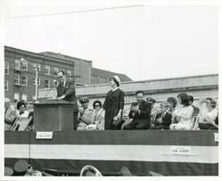 ["Black and white photograph print of Mary Albert standing at the dedication of the Carl Albert Parkway in McAlester, Oklahoma. Carl Albert, David Albert, and Mary Frances Albert are also pictured."]