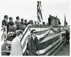 ["Black and white photograph print of Wilbur D. Mills speaking at the Port Carl Albert dedication. John N. Happy Camp, David Hall, Ed Edmondson, and others are present. May 27, 1972"]