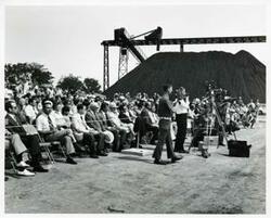["Black and white photograph print of several people at the Port Carl Albert dedication."]