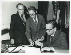 ["Black and white photograph print of presentation of $80,000 to Carl Albert for murals in Capitol. Fred Swengel and Gerald R. Ford are also present."]
