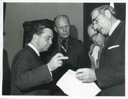 ["Black and white photograph print of presentation of $80,000 to Carl Albert for murals in Capitol. Fred Swengel and Gerald R. Ford are also present."]