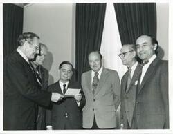 ["Black and white photograph print of presentation of $80,000 to Carl Albert for murals in Capitol. Fred Swengel and Gerald R. Ford are also present."]