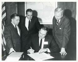 ["Black and white photograph print of Carl Albert, Ed Edmondson, and Secretary of Commerce John T. Conner watching Frank Lyons, Oklahoma State Highway director, sign a proclamation designating the Ozark Economic Development region. March 5, 1966"]