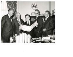 ["Black and white photograph print of Carl Albert, with four unidentified men, viewing a booklet on Talimena Scenic Drive"]