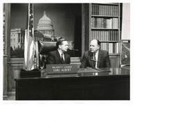 ["Black and white photograph print of Carl and commentator talking about the Robert S. Kerr Arboretum in his Majority Leader's office (without model)"]