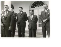 ["Black and white photograph print of John F. Kennedy with Carl Albert, Mike Mansfield, Hubert Humphrey, Hale Boggs, and Lyndon B. Johnson."]