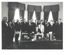 ["Black and White photograph, on stock paper, of John F. Kennedy signing S. 1643,the farm bill, in the president's office.  Those present include: Vice-President Lyndon B. Johnson, George Aiken, Carl Albert, Hubert H. Humphrey, W. R. Poage, James Eastland, and Sam Rayburn."]