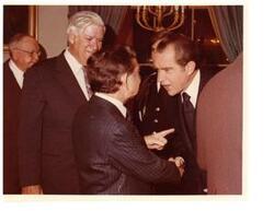 ["Color photograph print of President Richard Nixon shaking hands and speaking with Carl Albert.  Majority Leader Thomas O'Neill is also taking part in the conversation.  James O. Eastland also identified in the background"]