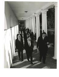 ["Black and white photograph of President Lyndon Johnson, House Speaker John W. McCormack; Representative Hale Boggs; Senator Carl Hayden; and Carl Albert walking outside"]