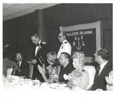 ["Black and white photograph of Carl Albert giving a speech at the United States Naval League Council in McAlester, Oklahoma on Armed Forces Day 1976."]