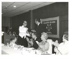 ["Black and white photograph of Carl Albert giving a speech at the United States Naval League Council in McAlester, Oklahoma on Armed Forces Day 1976."]