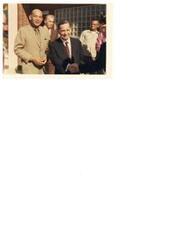 ["Color photograph of Carl Albert shaking hands with an unidentified veteran at a Veterans' event in Hugo, Oklahoma.  There is another unidentified man standing next to Carl in the photo."]