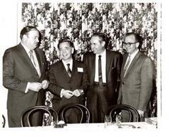["Black and white photograph of Carl Albert posing with three unidentified men at a dinner connected to a Disabled American Veteran state convention. 1970."]