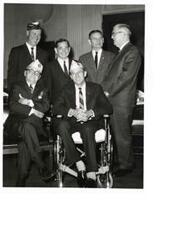 ["Black and white photograph of Carl Albert with some DAV unidentified members.  Man seated on the left (foreground) is D.A.V. Representative  Lambert Barkman."]