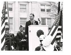 ["Black and white photograph of Carl Albert speaking at an outdoor American Legion event."]