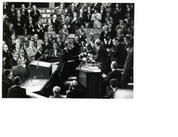["Black and white photograph of a group of men in the House chamber. Carl Albert and Gerald Ford are pictured."]