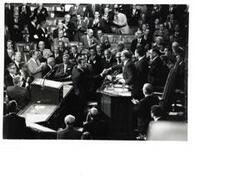 ["Black and white photograph of a group of men in the House chamber. Carl Albert and Gerald Ford are pictured."]