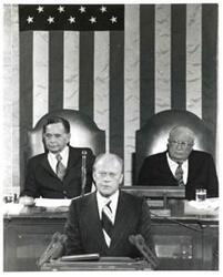 ["Black and white photograph of Gerald R. Ford standing at the speaker's podium. Carl Albert and James O. Eastland sitting behind him. Joint Session of Congress."]