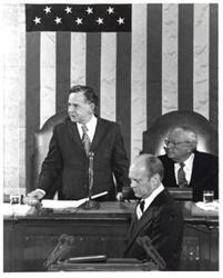["Black and white photograph of Gerald R. Ford standing at the speaker's podium. Carl Albert and James O. Eastland sitting behind him. Joint Session of Congress."]