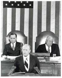 ["Black and white photograph of Gerald R. Ford standing at the speaker's podium. Carl Albert and James O. Eastland sitting behind him. Joint Session of Congress."]