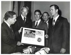 ["Black and white photograph of Carl Albert presenting Apollo 15 plaque to astronauts David Scott, Alfred Worden, and James Irwin. Albert's staff present in speaker's office. July 26, 1971"]