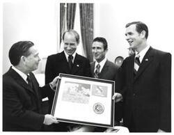["Black and white photograph of Carl Albert presenting Apollo 15 plaque to astronauts David Scott, Alfred Worden, and James Irwin. Albert's staff present in speaker's office. July 26, 1971"]