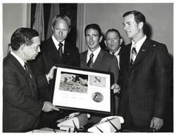 ["Black and white photograph of Carl Albert presenting Apollo 15 plaque to astronauts David Scott, Alfred Worden, and James Irwin. Albert's staff present in speaker's office. July 26, 1971"]