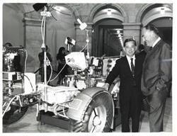 ["Black and white photograph of Carl Albert with unidentified man looking at the lunar rover."]