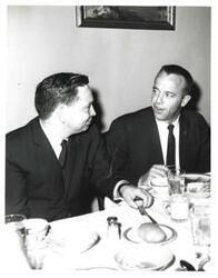 ["Black and white photograph of Carl Albert eating with an astronaut."]
