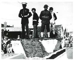 ["Black and white photograph of a parade in McAlester, Oklahoma on Armed Forces Day 1973"]