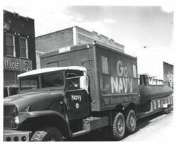 ["Black and white photograph of a parade in McAlester, Oklahoma on Armed Forces Day. 1977"]