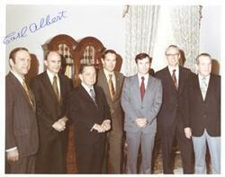 ["Color photograph of Carl Albert, James Fletcher (NASA administrator) and astronauts. John N. \"Happy\" Camp shown. In Speaker's office?  Photograph signed by Carl Albert."]