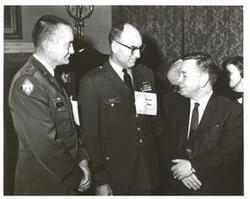 ["Black and white photograph of Carl Albert and two military officers at a reception in McAlester, Oklahoma on Armed Forces Day.  One officer's name tag lists them as General Weber."]