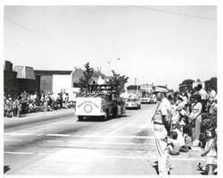 ["Black and white photograph of a parade in McAlester, Oklahoma on Armed Forces Day."]