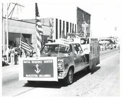 ["Black and white photograph of a parade in McAlester, Oklahoma on Armed Forces Day."]