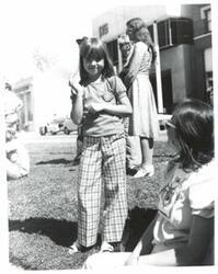 ["Black and white photograph of a young girl at a parade in McAlester, Oklahoma on Armed Forces Day."]