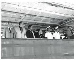 ["Black and white photograph of the speaker's stand in McAlester, Oklahoma on Armed Forces Day. Included left to right are Dewey F. Bartlett, Henry Bellmon, and Carl Albert."]