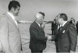 ["Black and white photograph print of Carl Albert shaking hands with an unidentified man at an airport."]