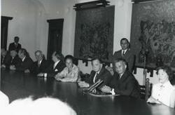 ["Black and white photograph print of Carl Albert and Mary Albert seated at a table with several others."]