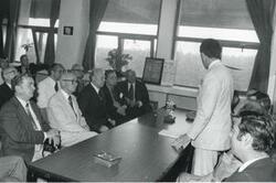 ["Black and white photograph print of unidentified man speaking to a group of men which includes Carl Albert. House delegation trip. August 1975"]