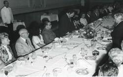 ["Black and white photograph print of  Carl Albert and several others seated at a dinner table. House delegation trip. August 1975"]