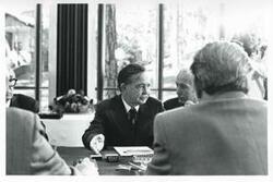 ["Black and white photograph print of Carl Albert talking with several men."]