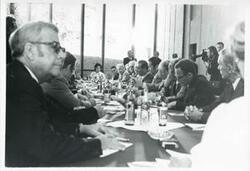 ["Black and white photograph print of Leonid Brezhnev seated with several other people during the House delegation trip. August 1975"]