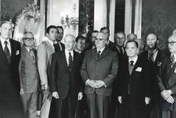 ["Black and white photograph print of Carl Albert, John Brademas, and several other men posing for a picture. House delegation trip. August 1975"]