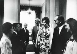 ["Black and white photograph print of Carl Albert speaking with an unidentified man and woman. Mary Albert is also present. House delegation trip. August 1975"]