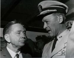 ["Black and white photograph of Carl Albert with military officers on a reviewing stand in McAlester, Oklahoma on Armed Forces Day. 1969. Not pictured is a note from U.S. Naval Captain R. M. Hanson to Carl Albert thanking him for participating in the Armed Service event; also a response letter from Carl Albert to Captain Hanson thanking him for the letter and his services are also not pictured."]