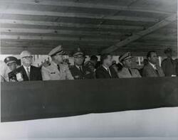 ["Black and white photograph of Carl Albert with military officers on a reviewing stand in McAlester, Oklahoma on Armed Forces Day. 1969. Not pictured is a note from U.S. Naval Captain R. M. Hanson to Carl Albert thanking him for participating in the Armed Service event; also a response letter from Carl Albert to Captain Hanson thanking him for the letter and his services are also not pictured."]