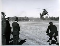 ["Carl Albert shown with military officers waiting for a helicopter to land. 1968"]