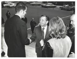 ["Black and white photograph of Carl Albert greeting someone outdoors."]